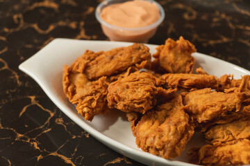 Close-up view of fried chicken served on a plate with sauces.