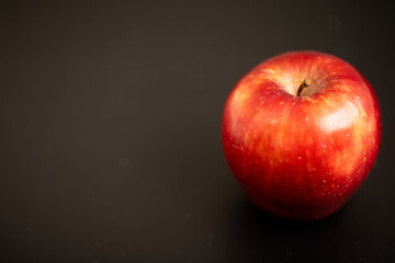 a bright red delicious apple on black background on the right side