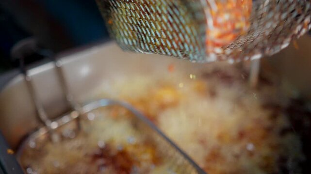 Close-up of crispy fried chicken pieces sizzling in hot oil inside a deep fryer in a Restaurant, showcasing delicious cooking in a kitchen.