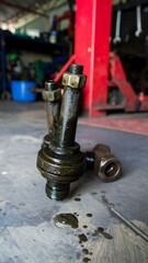 Dirty, oily mechanical part rests on a garage floor