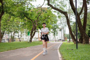 Young sporty woman jogging in the park listening to music with headphones