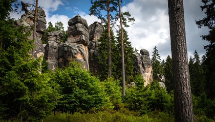Striking rock formations rise amidst a dense forest, bathed in natural sunlight.