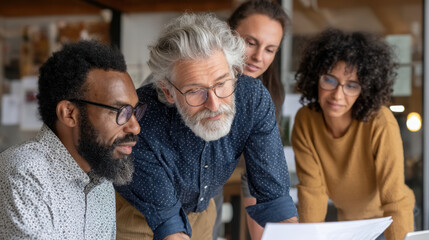 Collaborative team meeting with diverse professionals discussing project details. group includes senior man with gray hair and glasses, bearded man, and two women, one with curly hair