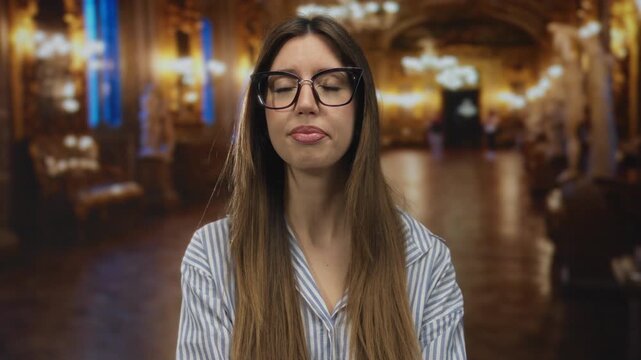 Woman pinches her nose with hand in ornate museum corridor lined with gilded columns under warm chandelier lighting; disgust.