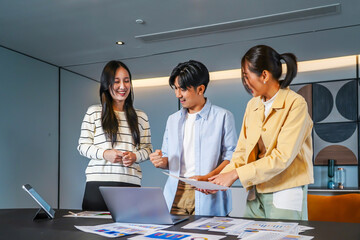This dynamic asian business team people group working with paperwork standing at table, analyzing corporate strategy, reviewing plan, managing financial project overview at office meeting
