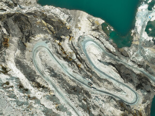 Aerial view of a transport truck hauling raw limestone through an open pit quarry, showing industrial mining operations and the environmental impact of material supply for global construction demand.
