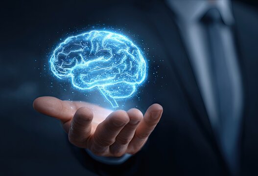 A hand, likely a businessman's, holds a holographic projection of a brain.  The brain is a light-blue, glowing, digital representation, floating above the palm
