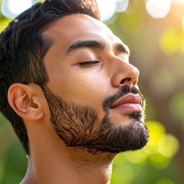 Close-up profile of a man with eyes closed,  dark hair and beard, peaceful expression, sunlit background