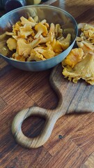Fresh chanterelles on a round wooden board on a light concrete background. Wild mushrooms, gifts of the forest.