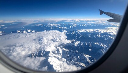 Airplane window view of snow-capped mountains and clouds