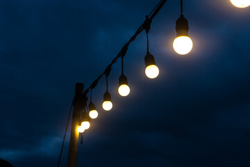 Old-fashioned streetlamps glow brightly against the dark night sky, illuminating the city street below