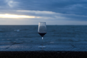 A single glass of chilled white wine on a table by the blue ocean and beach