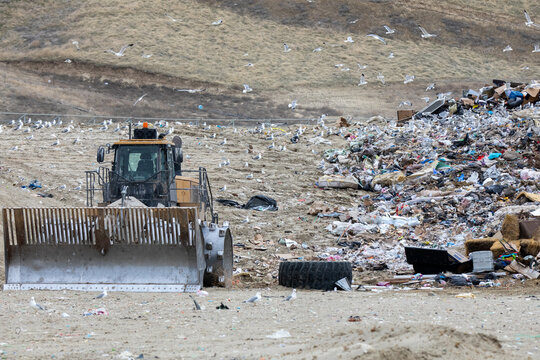 A large dump truck is driving through a pile of trash