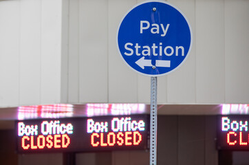 A sign for a pay station with a blue circle and arrow pointing to it
