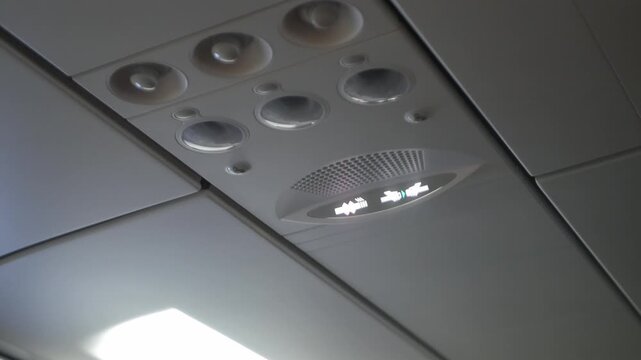 view inside airplane aircraft cabin to safety light sign overhead for fasten seatbelt and no smoking in airplane, safety sign light inside airplane for safe traveling