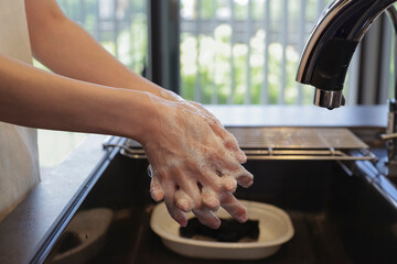 キッチンで手を洗う女性の手元（顔なし）