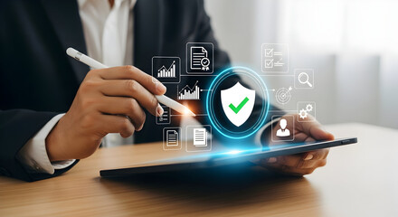 A person interacting with a digital tablet displaying a holographic security shield and various data management icons, symbolizing secure business operations and data protection.