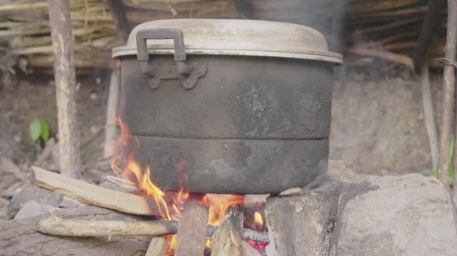 Close-up of blackened cooking pot over open firewood flames in rural Flores, Indonesia, used in traditional palm wine distillation