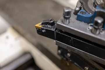Close-up of the tip of an interchangeable lathe tool in a machine.
