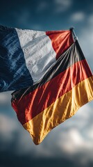 French and German flags wave together against a dramatic sky during a cultural event in Europe