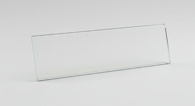 A clear rectangular acrylic nameplate sits angled on a light grey surface