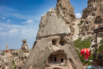 Old cave houses in natural rocks cones against modern buildings and mosque background. Uchisar castle Nevsehir Province in the Cappadocia region, Central Anatolia Turkey. Popular tourist attraction