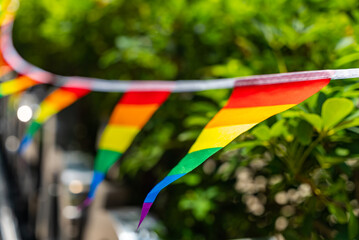Bright rainbow-striped bunting flags hanging and waving along the street during Bangkok Pride Parade. Symbol of LGBTQ visibility, unity, and celebration.