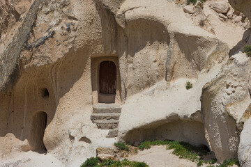Stone steps lead up to a small wooden door in the cave house at Uchisar castle in Cappadocia, Turkey. Uchisar castle at Nevsehir Province in Cappadocia region, Central Anatolia in Turkey