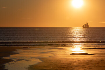 Fototapeta premium A boat in silhouette with a spectacular sunset at Cable beach in Broome, Western Australia.