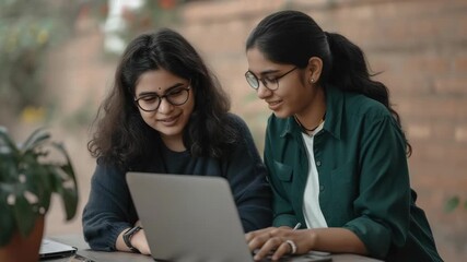 Two women focused on a laptop screen, possibly collaborating or learning together. - Powered by Adobe