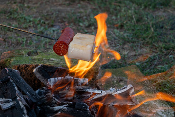 Traditional hungarian campfire cooking - bacon and sausage on a skewer