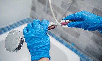 Woman's hands in gloves connecting the hose to a shower head