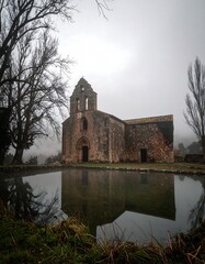 Fototapeta premium Misty ruin of a church reflected in a pond