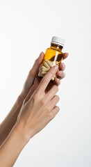 Fototapeta premium A brown pill bottle held by two hands with manicured nails against a white background