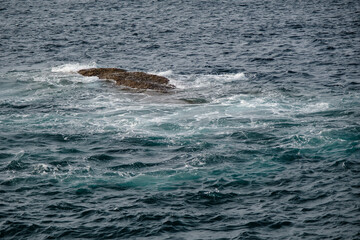 Naklejka premium small rocks at the open sea in cloudy sky summer day with empty copy space