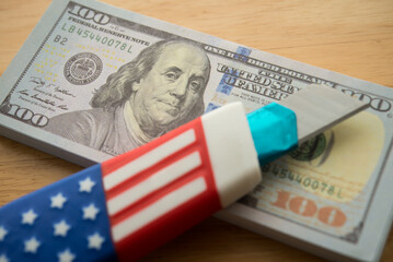 American flag cutter on US dollar banknotes. Central banking system of the United States FED (Federal Reserve System) cut interest rate to control monetary policy, world finance and economy concept.