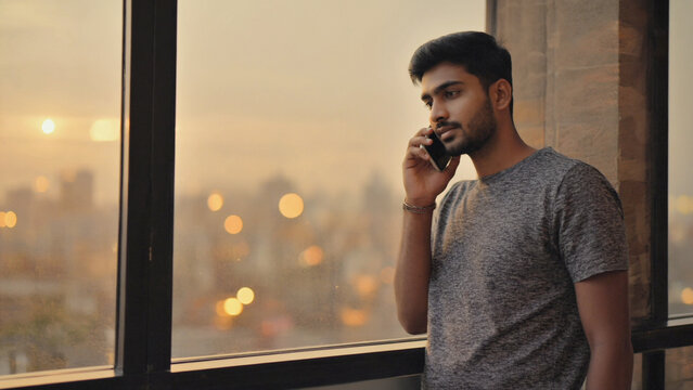 Serene Communication: A man engrossed in a phone conversation, silhouetted against the golden embrace of a sunset. - Powered by Adobe