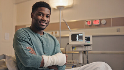 Fototapeta premium Patient's Resilience: A positive portrait of a patient sitting in a modern hospital room, his arm in a cast, exuding positivity and resilience with a warm smile and a sense of hope.