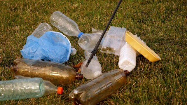 A close-up shot of a pair of plastic garbage collection tongs in a city setting. The idea of garbage collection and environmental protection is explored. A volunteer is seen collecting plastic trash.