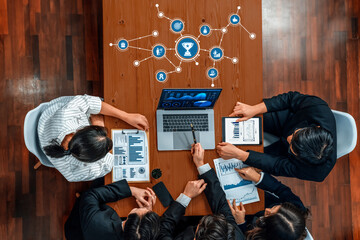 A diverse group of professionals collaborates in a modern office meeting, analyzing charts and data on a laptop while discussing strategies and insights for their project. Amity