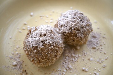Traditional homemade plum dumplings served on yellow plate, close-up view.