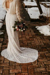 Bride in Lace Dress Holding Bouquet on Brick Path in Winter