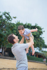 Father and young toddler son walk and play in the sand on the beach in Bali, Indonesia