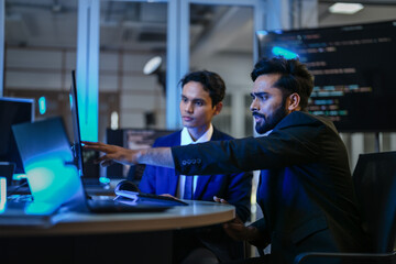 Fototapeta premium A diverse team of AI developers shares a successful moment in the office. A female programmer smiles as they review the positive results of a complex machine learning algorithm.