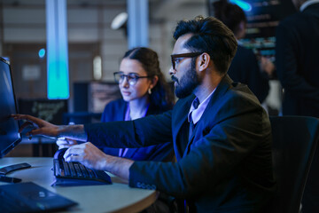 A diverse team of AI developers shares a successful moment in the office. A female programmer smiles as they review the positive results of a complex machine learning algorithm.