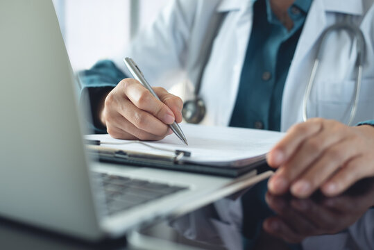 Doctor filling paper medical records. Doctor working with medical report document clipboard, health insurance claim form, with laptop computer at office, writing note, prescription. Close up - Powered by Adobe