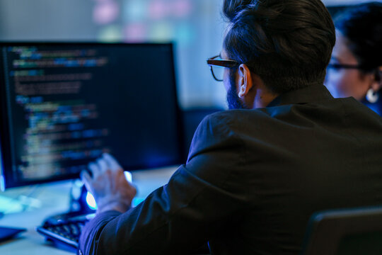 A backend AI developer programs a complex algorithm late at night in a data center. A focused engineer architecting a new machine learning system for data analysis or cybersecurity.