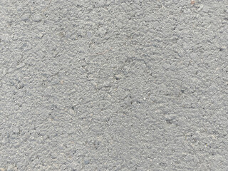 Rough Gray Asphalt Surface with Embedded Stones and Uneven Texture