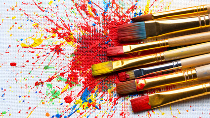 Obraz premium Artistic canvas with colorful paint splashes and brushes