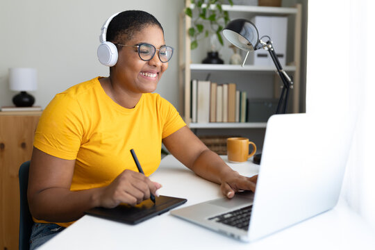 Smiling graphic designer working from home using graphics tablet and laptop